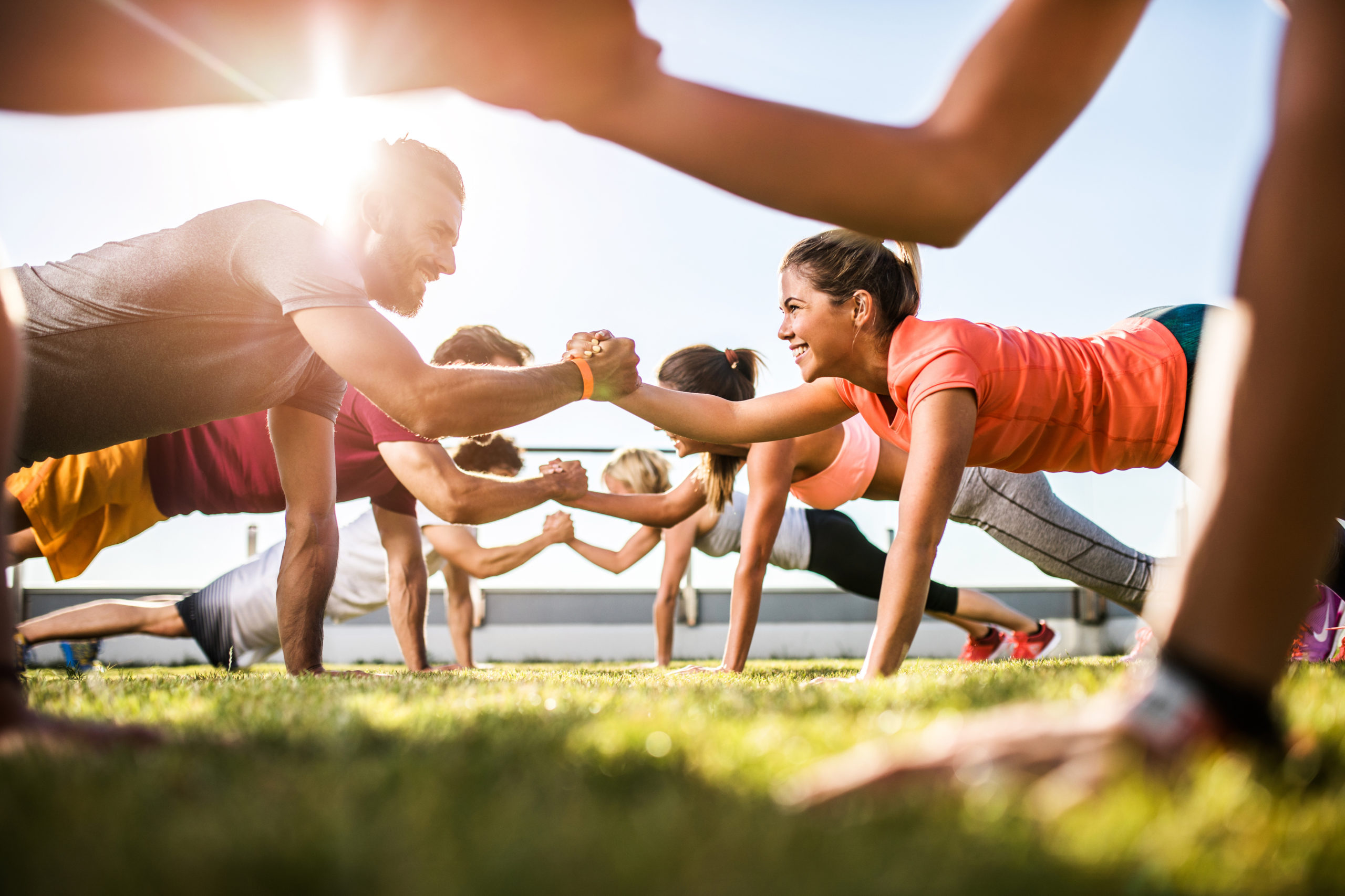 Happy athletic people cooperating while exercising on a sports training.